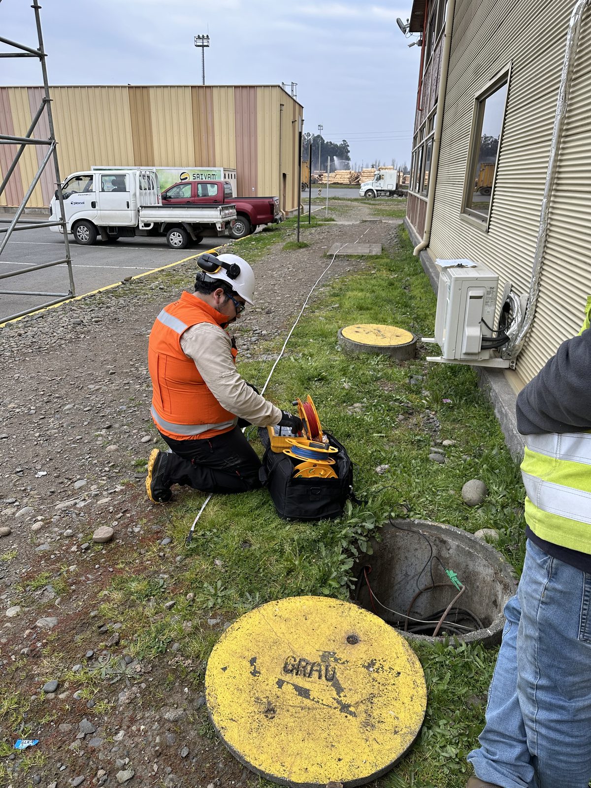 Técnico realizando medición en cámara de registro eléctrico